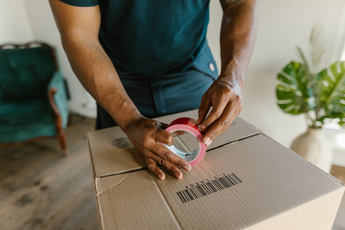 man taping up a moving box to prepare for his individual move to Bangladesh with Atlas International